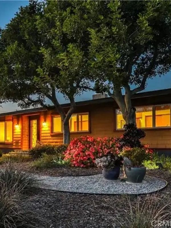 Cozy house with warm lights and a well-kept garden at dusk.