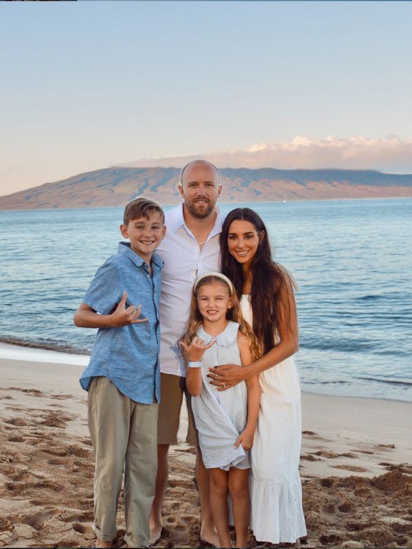 Family posing happily on a beach at sunset.