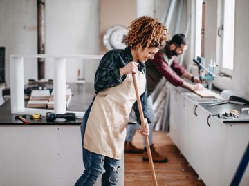 A man and a woman cleaning up after construction work in a kitchen.