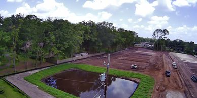 Construction site with a water retention pond and heavy machinery.