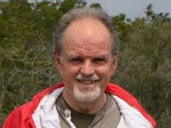 Smiling man outdoors wearing a red jacket.