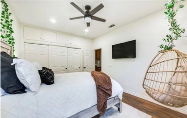 Cozy modern bedroom with a hanging chair and ceiling fan.