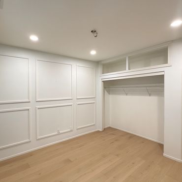 Empty modern room with light wood floors and white paneled walls.
