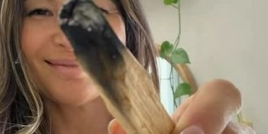 A woman holding a smudging stick with a smile.