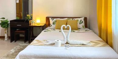 Cozy bedroom with yellow accents and towel swans on the bed.