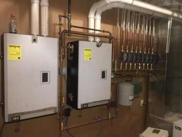 Two wall-mounted IBC boilers with connected copper piping and valves.