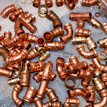A collection of copper plumbing fittings scattered on a surface.