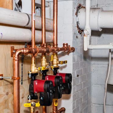 Copper piping system with red water pumps in a basement.