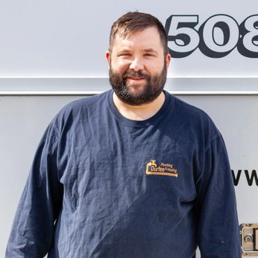 Smiling man wearing a navy blue Durfee Plumbing & Heating shirt.