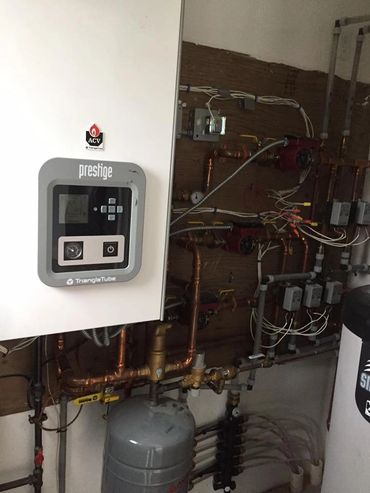 Heating system with pipes and control unit on a wall.