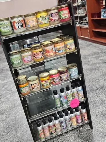 Display shelf with various scented candles and sprays in a store.