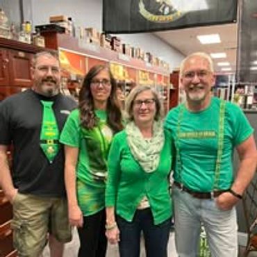 Four adults wearing green clothing, smiling indoors.
