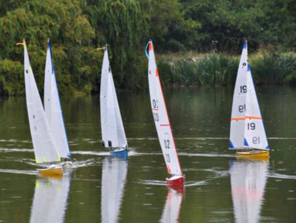 Model sailboats with white sails sailing on calm water.