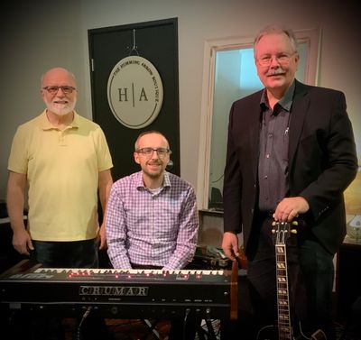 Three men with musical instruments in a room.