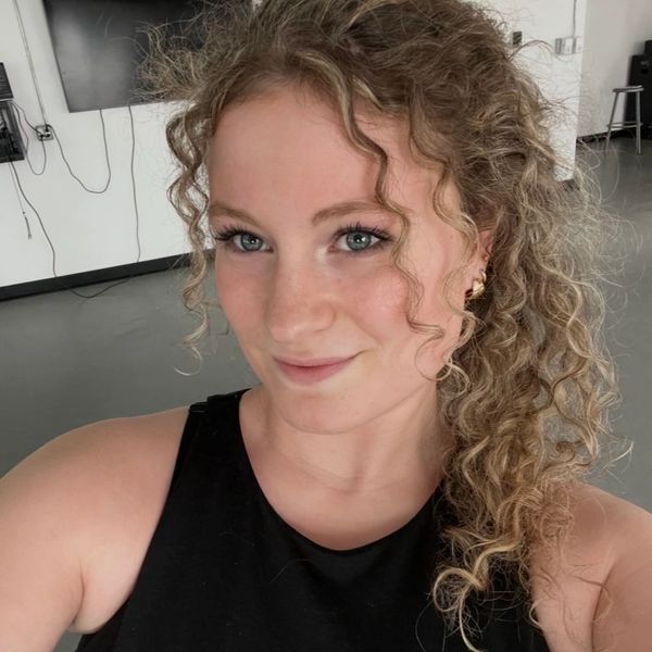 A woman with curly hair and blue eyes smiling indoors.