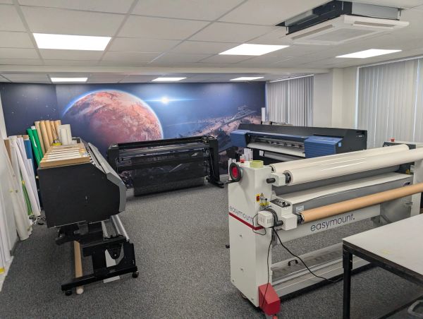 Room with printing machines and space-themed wall art.