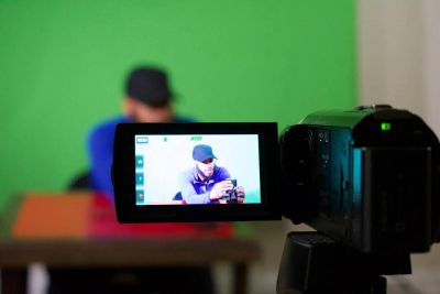 Person recorded on camera in front of a green screen.