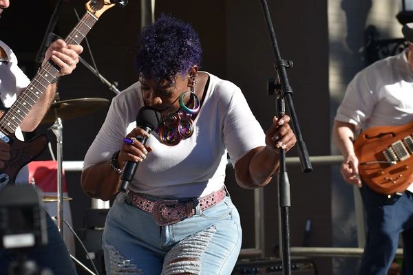 Singer passionately performing on stage with guitarists.