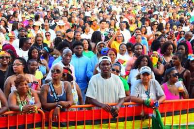 Large diverse crowd at an event behind a barrier.