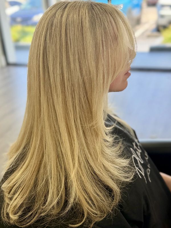 Side view of smooth, layered blonde hair with soft curls at the ends.