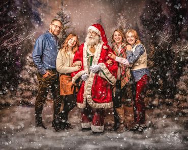 Painterly portrait of Family of four with Santa in front of snowy pines backdrop