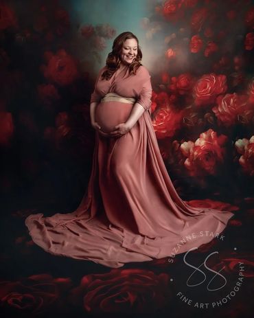 Maternity portrait of mother in rose colored fabric draping around her, on backdrop of roses