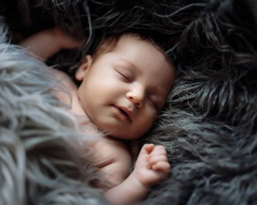 Sleeping baby on gray fur fabric