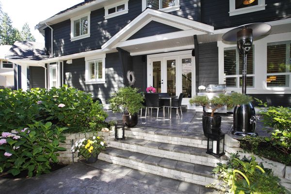 Modern house entrance with plants and outdoor furniture.
