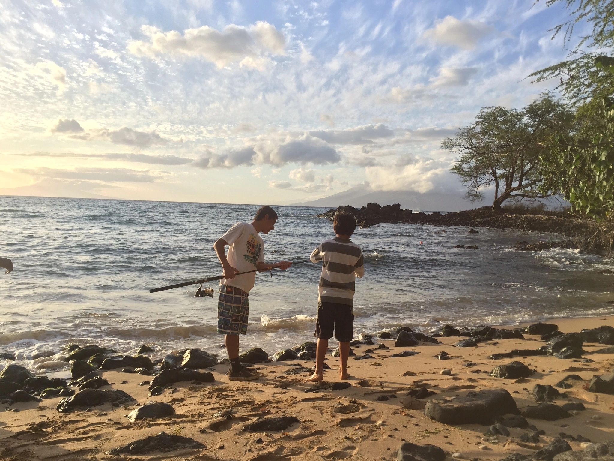 Two brothers, Kolomona and Kaulana, work together to string a fishing pole.  Working together, we ac
