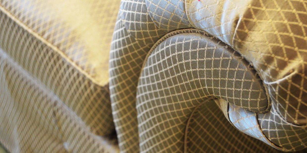 Close-up of a patterned fabric sofa armrest with intricate stitching.