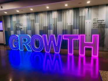 Neon letters spelling GROWTH at J.B. Hunt office with company values displayed.