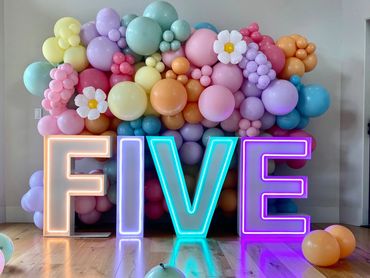 Colorful balloon arrangement spelling 'FIVE' with neon lights.
