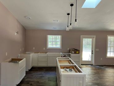 Kitchen under renovation with white cabinets and pendant lights