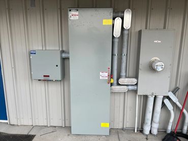 Three-phase commercial generator equipment and disconnects on a metal building