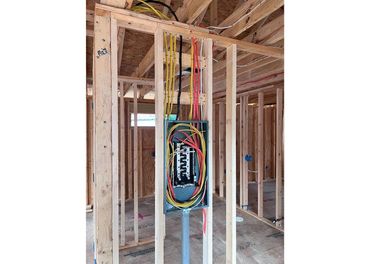 Electrical panel with organized wiring in the wood framing of a new building