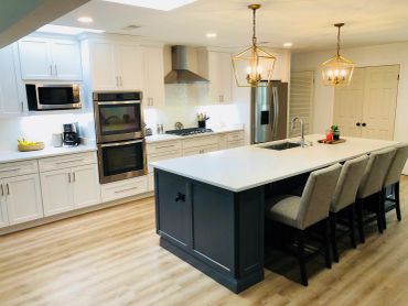 Modern kitchen with white cabinets, stainless steel appliances, and a large island with seating.