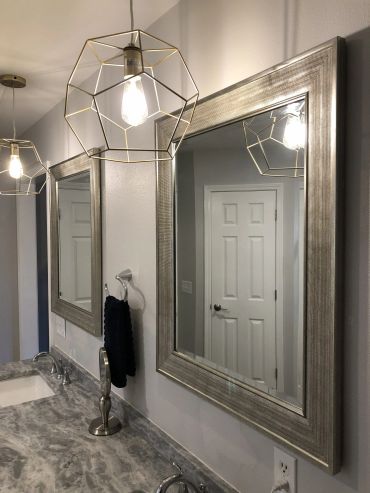 Modern bathroom with geometric pendant lights and large mirrors.