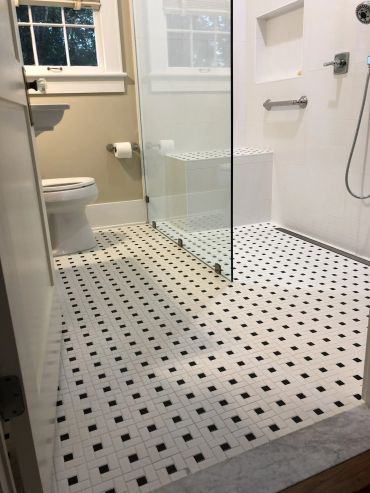 Modern bathroom with black and white tiled floor and glass shower.