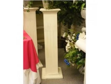Tall, narrow white pedestal with plant decor around.