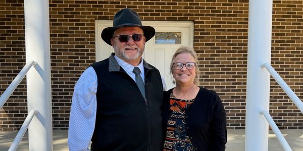 Smiling couple standing outside a brick building with white pillars.