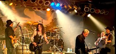 The Dead Cowboys band performing live on stage with vibrant lighting.