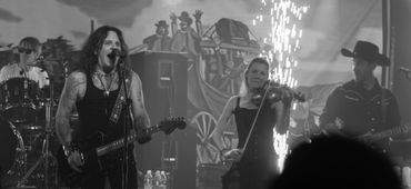 Bobby Jensen and Kat performing live with guitar, violin, and energetic stage effects.
