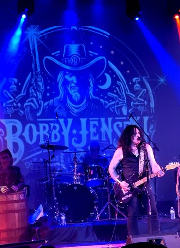 Rock band Bobby Jensen performing live with vibrant blue and red lights.