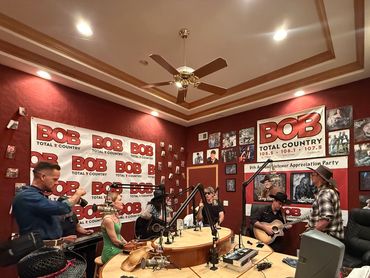 A lively country music radio show with musicians playing instruments inside a studio.