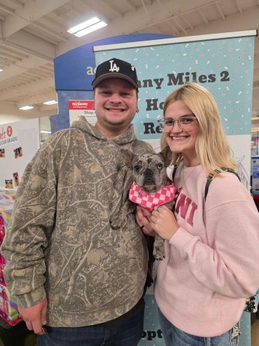 Happy couple holding a dog at a pet adoption event.