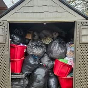 Shed filled with black garbage bags and red bins.