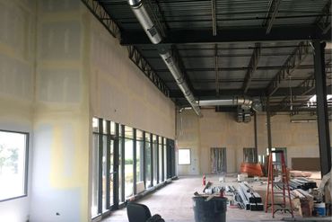 Interior of a commercial space under construction with exposed ductwork and building materials.