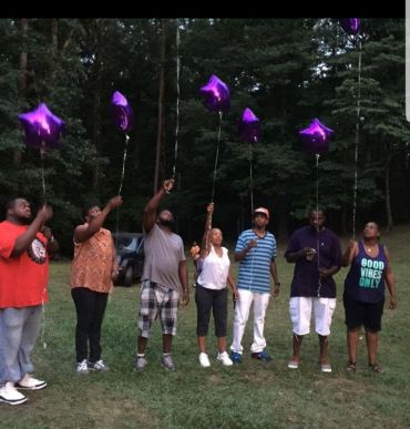 Group releasing purple star-shaped balloons in a park.