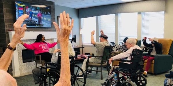 Elderly people in a group exercise session following a TV instructor.