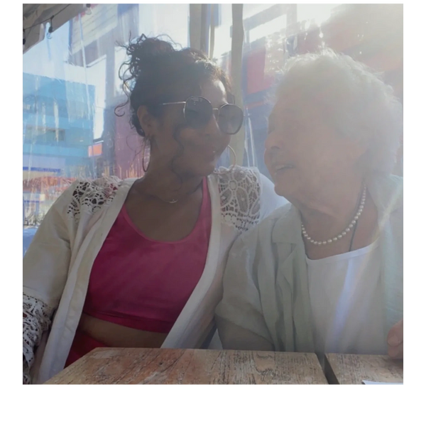 Two women sharing a warm moment at a sunlit table.